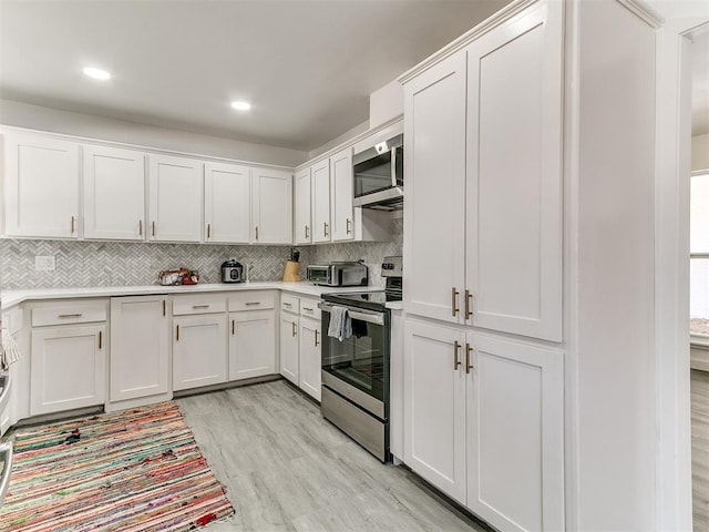 6001 Broadmoor Ave, Oklahoma City, OK 73132 - kitchen with stainless steel appliances, decorative backsplash, light countertops, light wood-style flooring, and white cabinetry