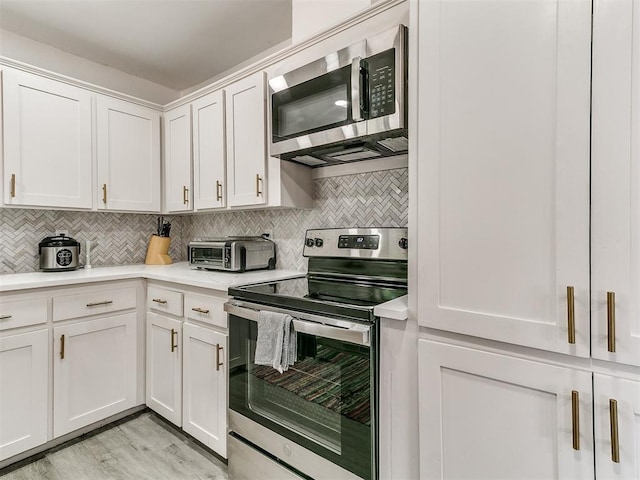 6001 Broadmoor Ave, Oklahoma City, OK 73132 - kitchen with appliances with stainless steel finishes, light countertops, backsplash, and white cabinetry
