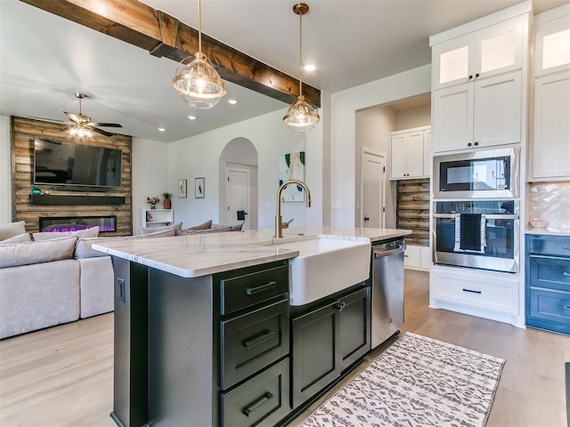 222 Alamosa Rd, Norman, OK 73069 - kitchen featuring appliances with stainless steel finishes, a sink, arched walkways, white cabinets, and light wood finished floors