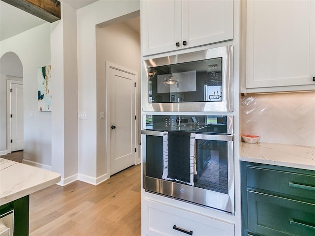 222 Alamosa Rd, Norman, OK 73069 - kitchen featuring appliances with stainless steel finishes, light wood finished floors, light stone countertops, baseboards, and arched walkways