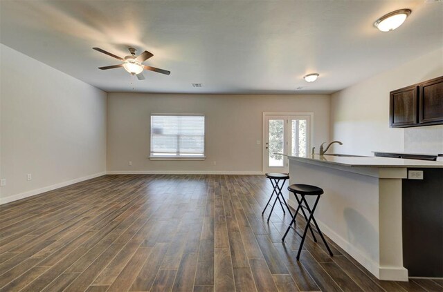 9749 Livingston Rd, Edmond, OK 73025 - kitchen with a breakfast bar area, ceiling fan, dark wood-style flooring, baseboards, and dark brown cabinetry