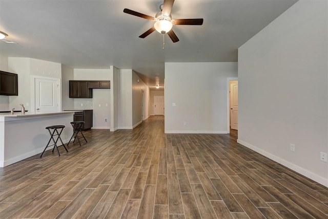 9749 Livingston Rd, Edmond, OK 73025 - unfurnished living room with dark wood-type flooring, ceiling fan, and baseboards