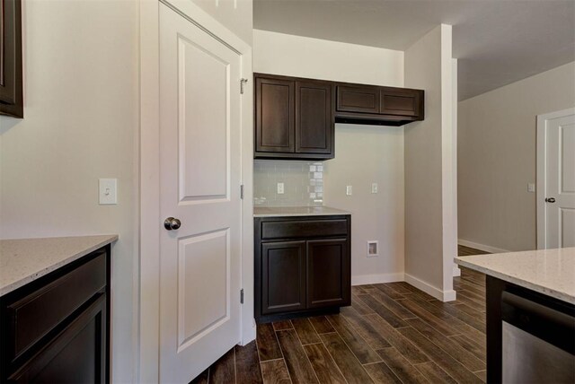 9749 Livingston Rd, Edmond, OK 73025 - kitchen featuring baseboards, dark brown cabinets, dark wood-style floors, backsplash, and light stone counters