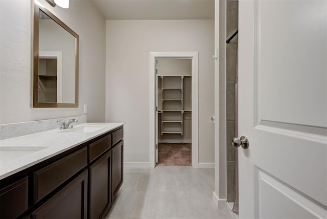 9749 Livingston Rd, Edmond, OK 73025 - bathroom featuring double vanity, a walk in closet, baseboards, a shower, and tile patterned flooring