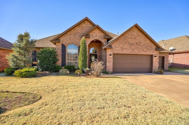924 Regal Rd, Yukon, OK 73099 - view of front of house with brick siding, an attached garage, a front lawn, and driveway