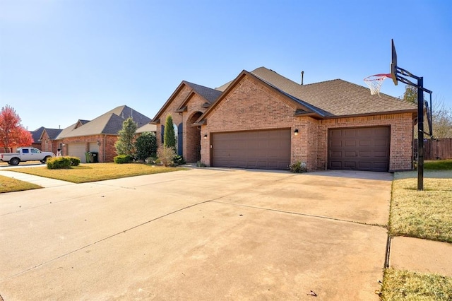 924 Regal Rd, Yukon, OK 73099 - view of front of home with brick siding, concrete driveway, an attached garage, and roof with shingles