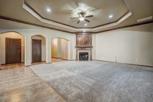 924 Regal Rd, Yukon, OK 73099 - unfurnished living room featuring a tray ceiling, a ceiling fan, crown molding, arched walkways, and baseboards