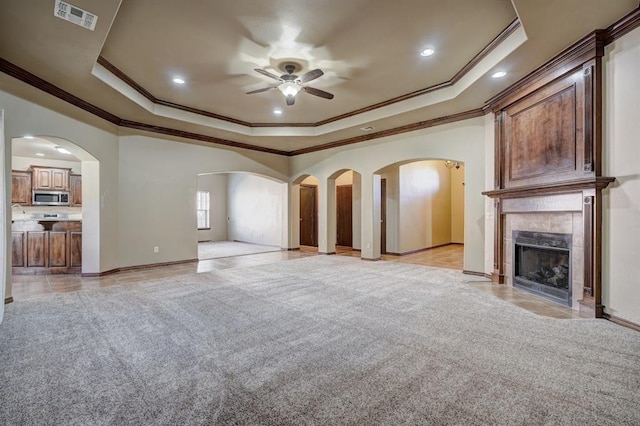 924 Regal Rd, Yukon, OK 73099 - unfurnished living room with a tray ceiling, ceiling fan, ornamental molding, light tile patterned floors, and a tiled fireplace