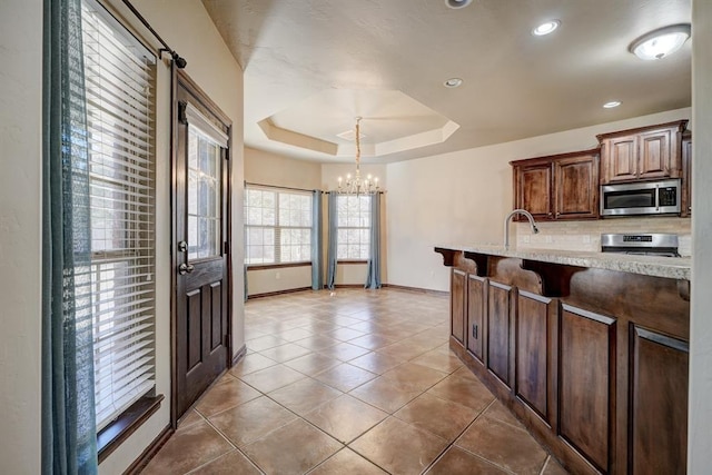 924 Regal Rd, Yukon, OK 73099 - kitchen featuring stainless steel appliances, a chandelier, a raised ceiling, baseboards, and light tile patterned floors