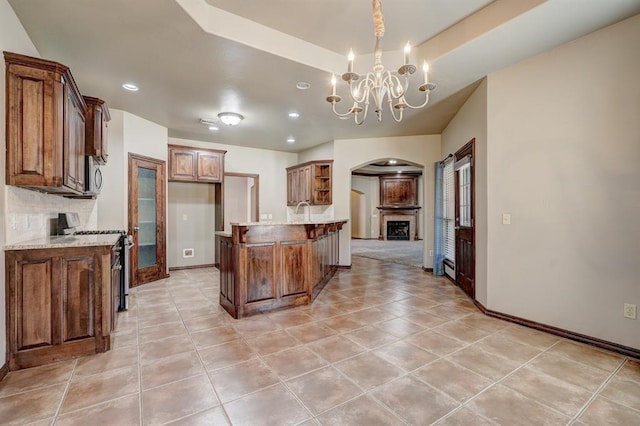 924 Regal Rd, Yukon, OK 73099 - kitchen with appliances with stainless steel finishes, arched walkways, a peninsula, a chandelier, and light tile patterned floors