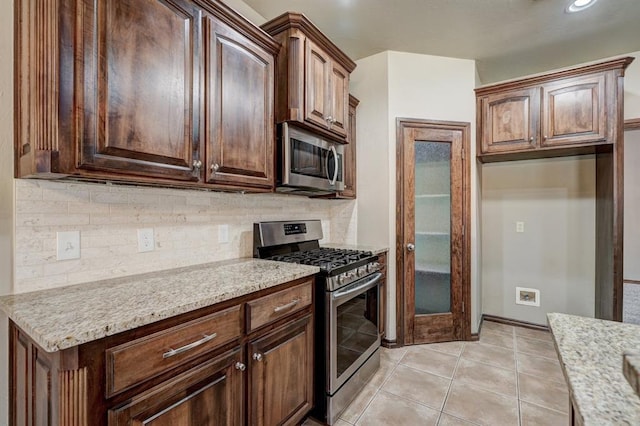 924 Regal Rd, Yukon, OK 73099 - kitchen with appliances with stainless steel finishes, backsplash, light stone countertops, and light tile patterned flooring