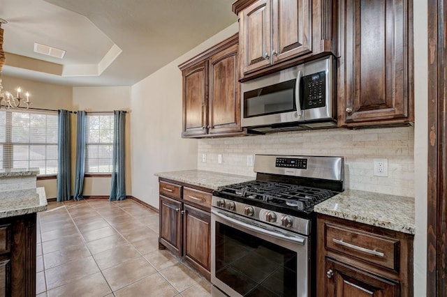 924 Regal Rd, Yukon, OK 73099 - kitchen featuring appliances with stainless steel finishes, backsplash, a chandelier, light tile patterned floors, and baseboards