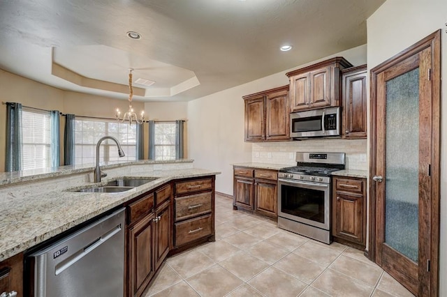 924 Regal Rd, Yukon, OK 73099 - kitchen featuring stainless steel appliances, a sink, tasteful backsplash, a chandelier, and a tray ceiling