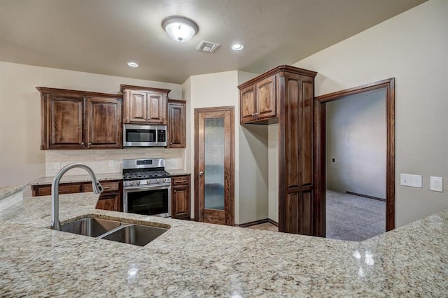 924 Regal Rd, Yukon, OK 73099 - kitchen featuring stainless steel appliances, a sink, light stone counters, and decorative backsplash
