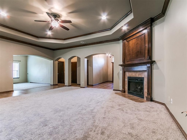 924 Regal Rd, Yukon, OK 73099 - unfurnished living room featuring ornamental molding, arched walkways, a raised ceiling, light carpet, and recessed lighting