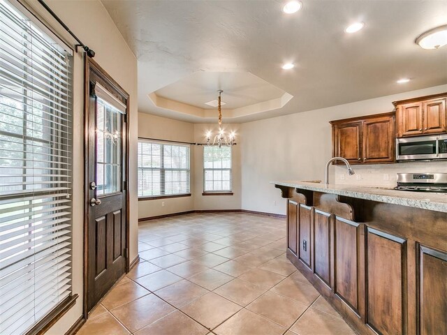 924 Regal Rd, Yukon, OK 73099 - kitchen featuring appliances with stainless steel finishes, a chandelier, light tile patterned flooring, a tray ceiling, and baseboards