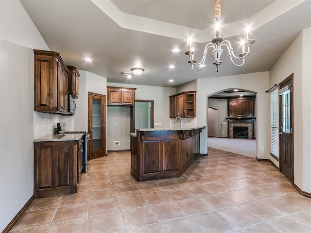924 Regal Rd, Yukon, OK 73099 - kitchen with range with gas cooktop, arched walkways, open shelves, light tile patterned flooring, and a chandelier