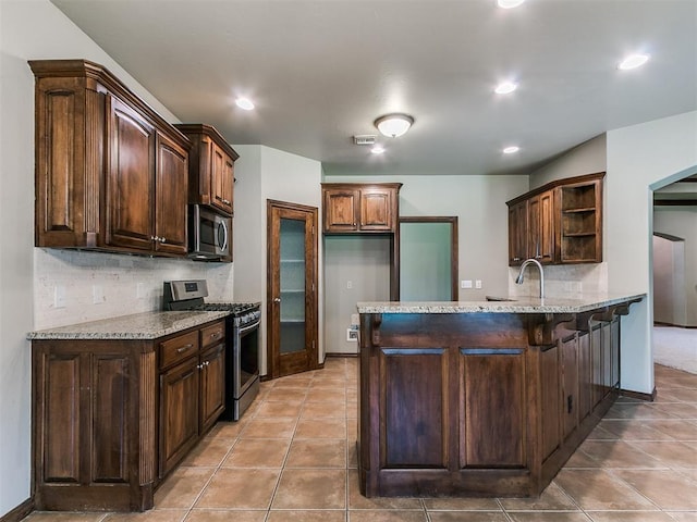 924 Regal Rd, Yukon, OK 73099 - kitchen featuring stainless steel appliances, open shelves, a peninsula, decorative backsplash, and light stone countertops