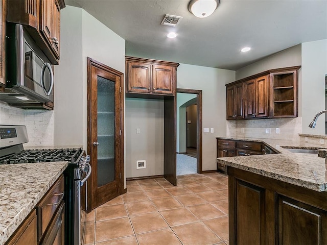 924 Regal Rd, Yukon, OK 73099 - kitchen with appliances with stainless steel finishes, a sink, open shelves, arched walkways, and light stone counters