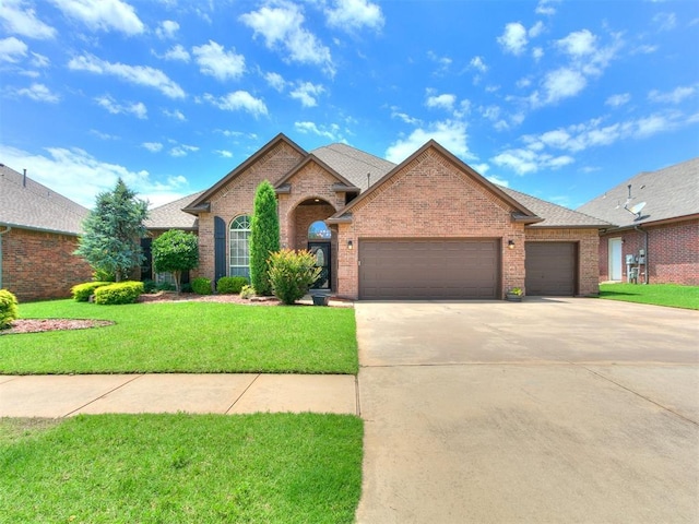 924 Regal Rd, Yukon, OK 73099 - view of front of house featuring brick siding, a garage, a front yard, and driveway