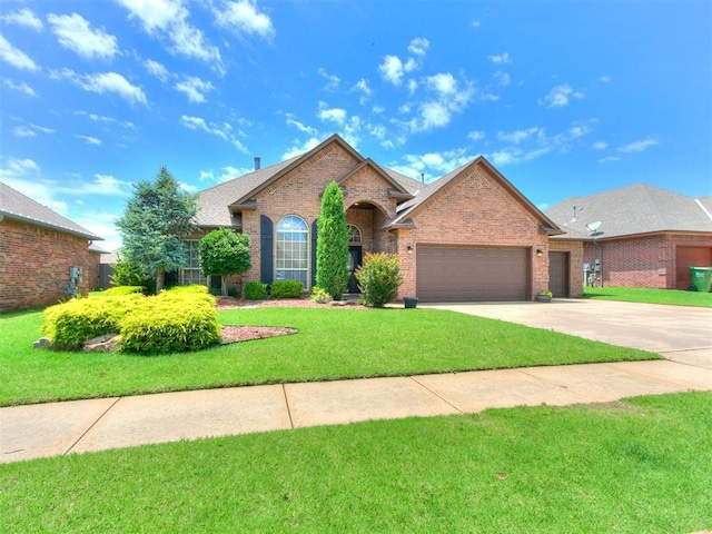 924 Regal Rd, Yukon, OK 73099 - view of front of house featuring an attached garage, brick siding, concrete driveway, a front lawn, and roof with shingles