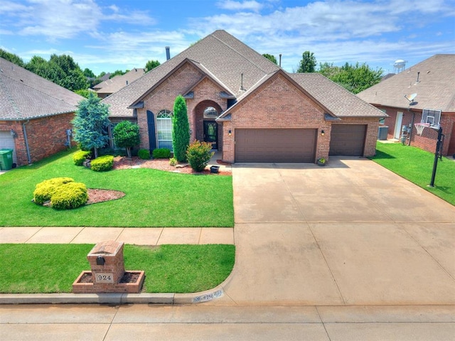 924 Regal Rd, Yukon, OK 73099 - view of front facade with brick siding, an attached garage, a front yard, and concrete driveway