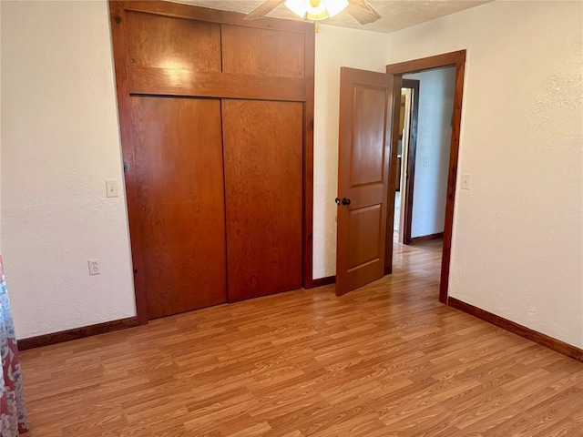 321 E Ninth St, Leedey, OK 73654 - unfurnished bedroom with light wood finished floors, a closet, baseboards, a textured wall, and ceiling fan
