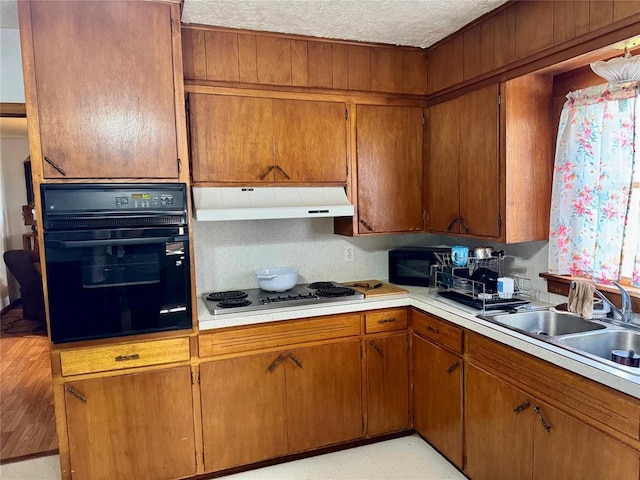 321 E Ninth St, Leedey, OK 73654 - kitchen featuring black appliances, under cabinet range hood, light countertops, brown cabinets, and a textured ceiling