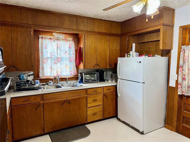 321 E Ninth St, Leedey, OK 73654 - kitchen with freestanding refrigerator, brown cabinetry, light countertops, a sink, and a textured ceiling