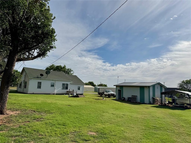 321 E Ninth St, Leedey, OK 73654 - rear view of property featuring a carport, a lawn, and an outbuilding