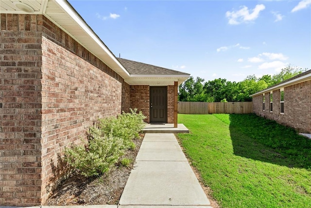 doorway to property with brick siding and roof with shingles