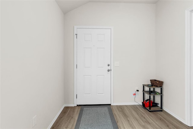 doorway to outside with wood finished floors, baseboards, and vaulted ceiling
