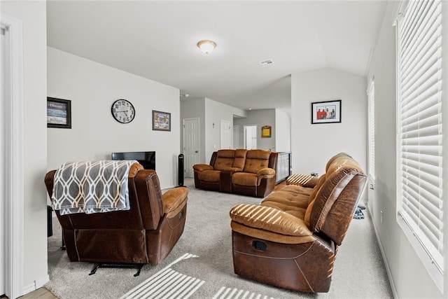 carpeted living area featuring lofted ceiling, plenty of natural light, and baseboards