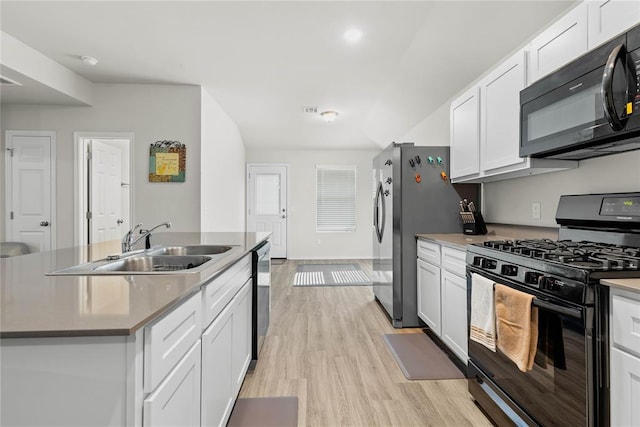 kitchen featuring black appliances, a sink, light wood-style floors, white cabinets, and a center island with sink