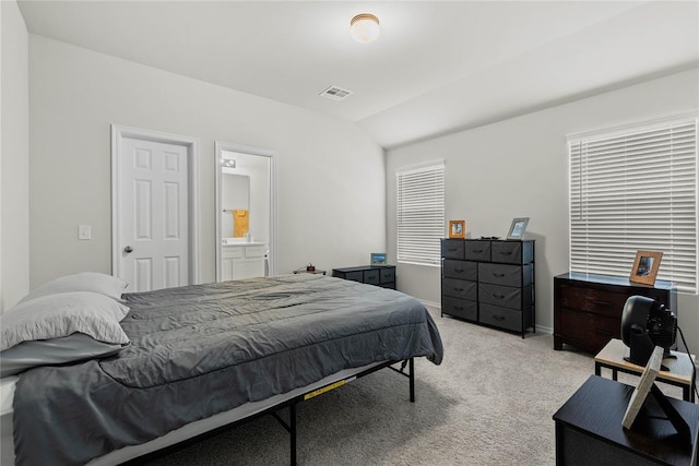 bedroom with light colored carpet, vaulted ceiling, connected bathroom, baseboards, and a desk
