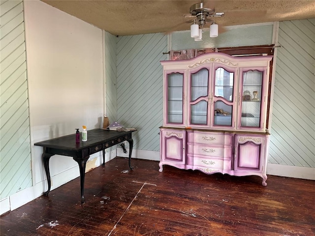 711 E Walnut St, Altus, OK 73521 - home office featuring wood walls, dark wood-style flooring, ceiling fan, a textured ceiling, and baseboards