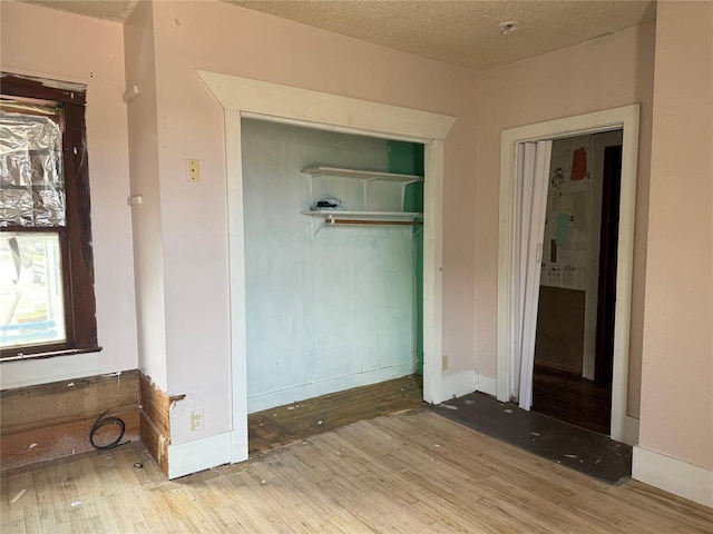 711 E Walnut St, Altus, OK 73521 - unfurnished bedroom featuring wood finished floors, a closet, a textured ceiling, and baseboards