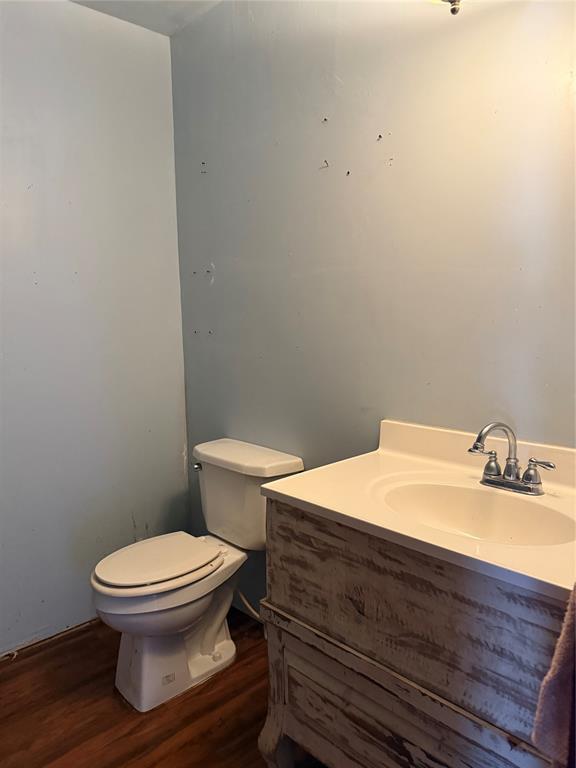 711 E Walnut St, Altus, OK 73521 - half bathroom featuring toilet, wood finished floors, and vanity