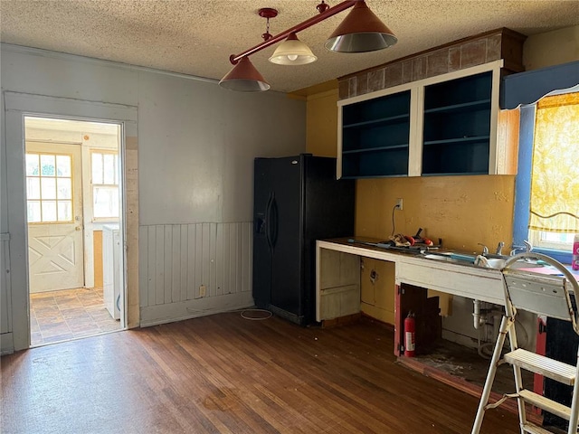 711 E Walnut St, Altus, OK 73521 - kitchen featuring black fridge, healthy amount of natural light, a textured ceiling, wood finished floors, and open shelves
