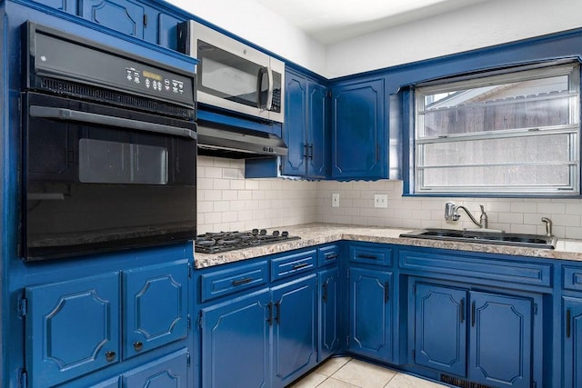 kitchen featuring black oven, stainless steel microwave, a sink, gas cooktop, and blue cabinetry