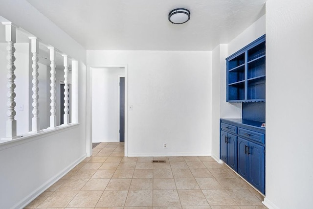 spare room featuring light tile patterned floors and baseboards