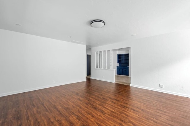 spare room with dark wood-type flooring and baseboards