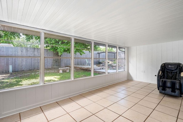 unfurnished sunroom featuring tile patterned flooring and wood walls