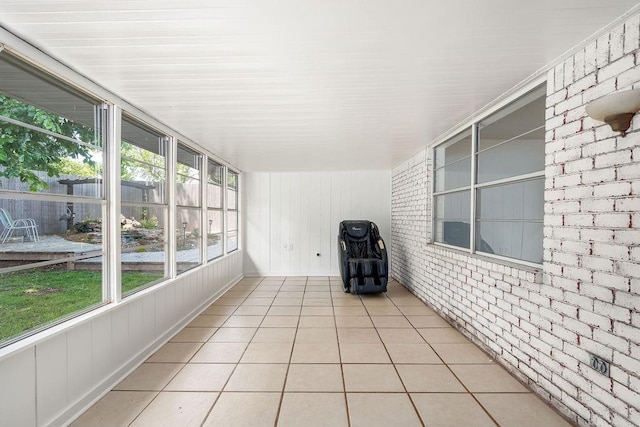 unfurnished sunroom with healthy amount of natural light, brick wall, and tile patterned floors