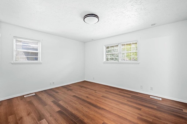 empty room with wood finished floors, a textured ceiling, and baseboards