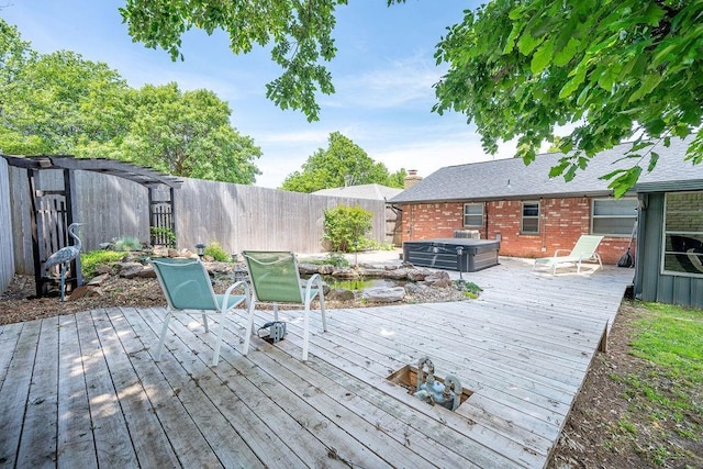 wooden deck featuring a hot tub and a fenced backyard