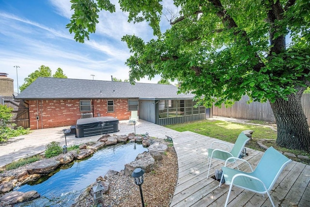 wooden deck with a hot tub, a fenced backyard, a garden pond, and a sunroom