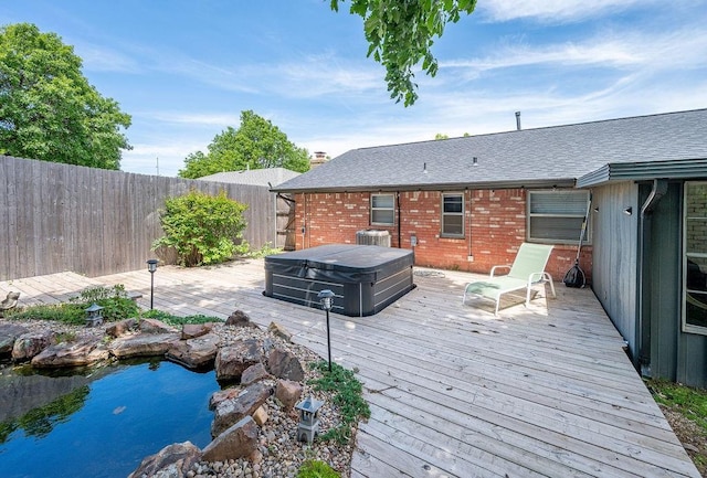 wooden terrace with a covered hot tub and a fenced backyard