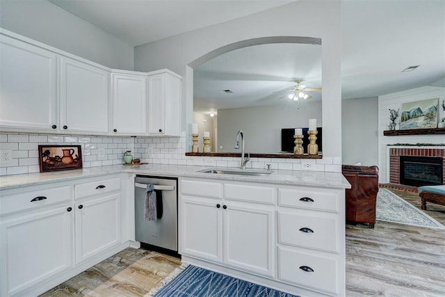 12308 Hickory Creek Blvd, Oklahoma City, OK 73170 - kitchen with stainless steel dishwasher, a sink, light wood-style flooring, arched walkways, and decorative backsplash