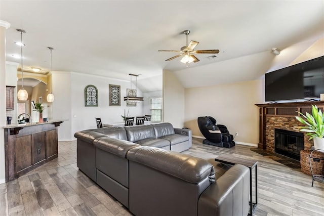 12116 NW 137th St, Piedmont, OK 73078 - living room featuring a ceiling fan, a stone fireplace, light wood-style flooring, baseboards, and lofted ceiling
